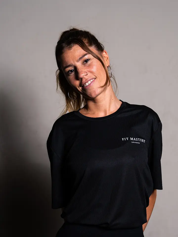 Person wearing a black Fit Mastery branded t-shirt, smiling at the camera