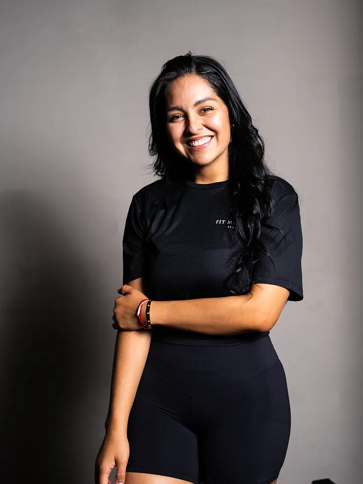 A person wearing black athletic top and shorts, standing with crossed arms