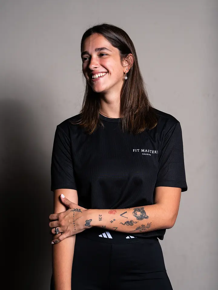A staff member wearing Fit Mastery branded black clothing, smiling with arms crossed